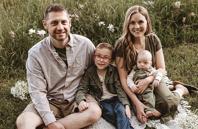 The Anthony family sitting on a blanket in a grassy field with flowers.