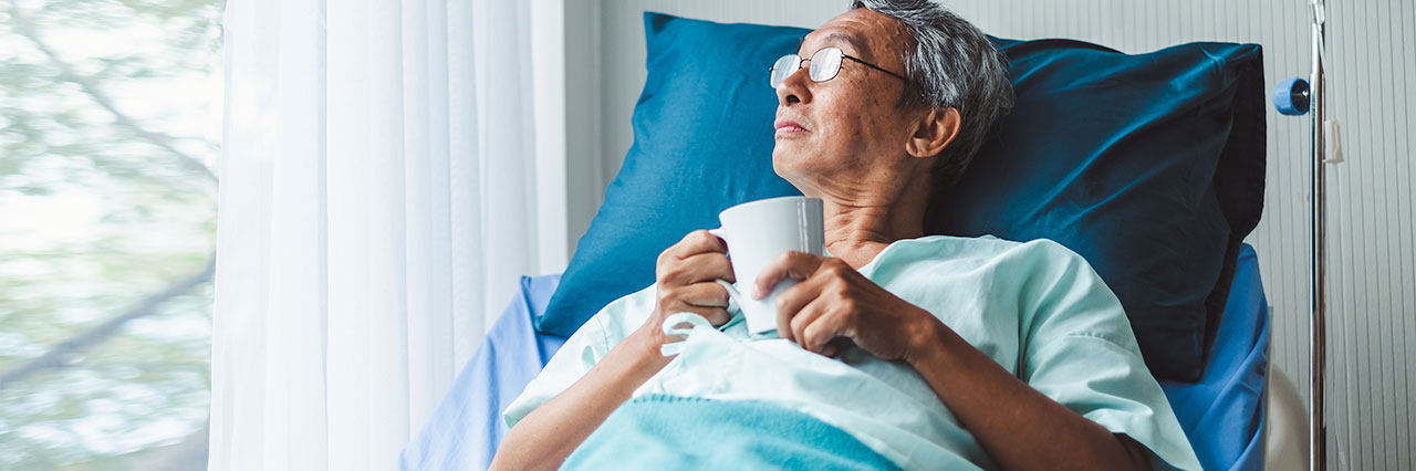 Cancer patient looking out of the window in his hospital bed