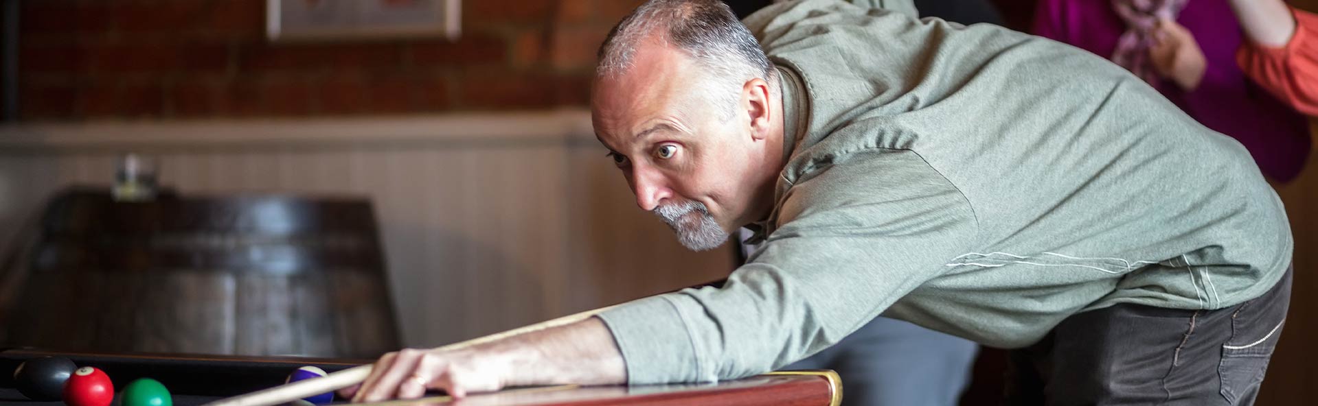 mature male playing billiards.