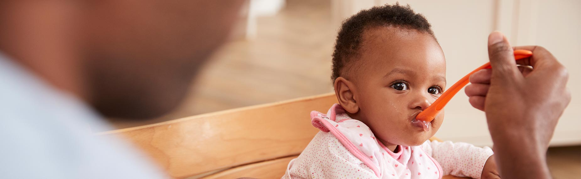 Father Feeding Baby Daughter In High Chair