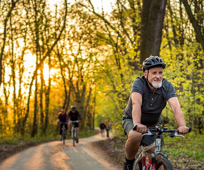 Man biking with friends outside on a trail