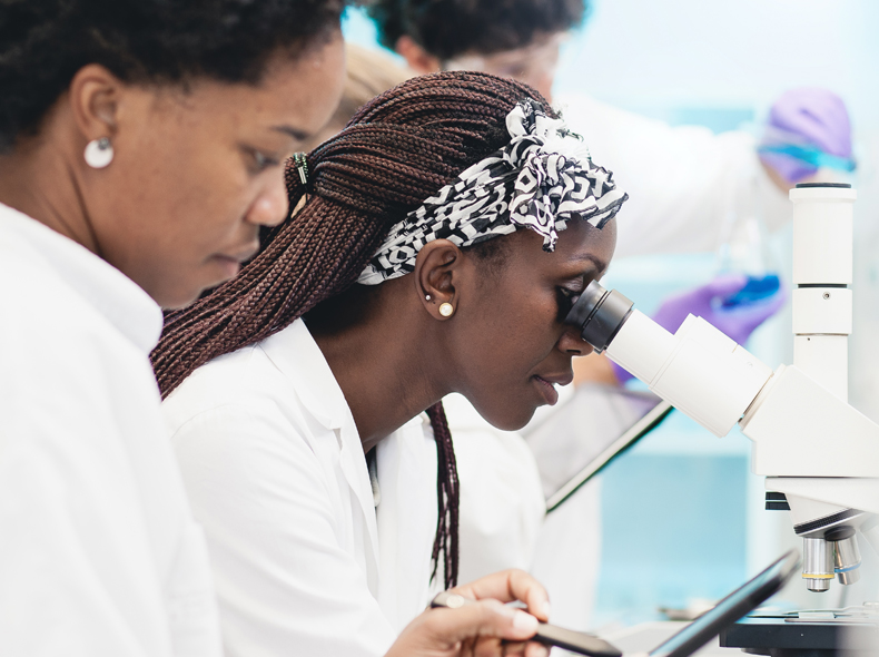 Two female students looking through a microscope