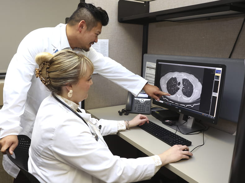 Two medical staff members looking at a computer monitor