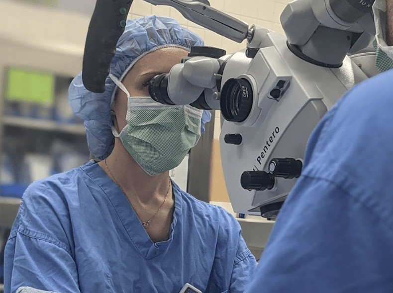 A medical professional looking into microscope