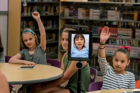 Students participate in class, including one via Apple iPad.