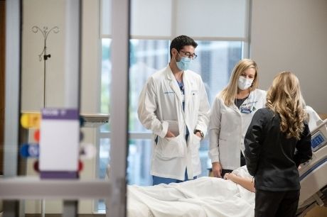 Patient care team surrounding a bed.