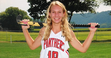 Leah in team uniform with her filed hockey stick