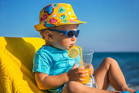 little boy drinking water on beach