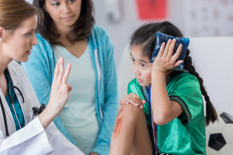 Girl holds ice pack to head while being examined for a concussion