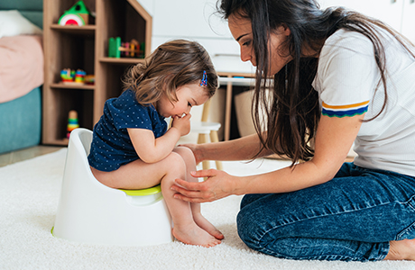 A mom potty training her child on the toilet