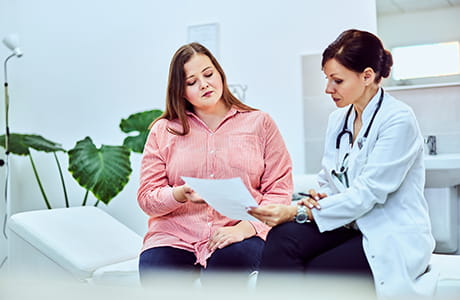 A professional female nutritionist showed a diet plan to her overweight female patient.