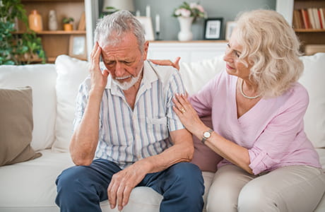 Senior man with pained expression on his face due to a headache woman comforting him. 