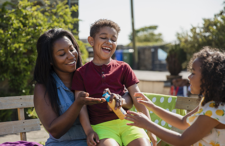 A family playing outside and putting on sunblock.