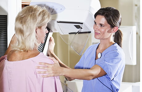 Woman, 50s, with nurse or technician, getting a mammogram. 