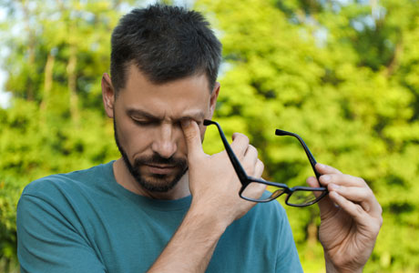 a man rubbing his eye while holding his glasses in one hand