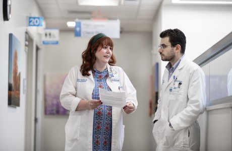 Two palliative medicine specialist talk in a hospital hallway.