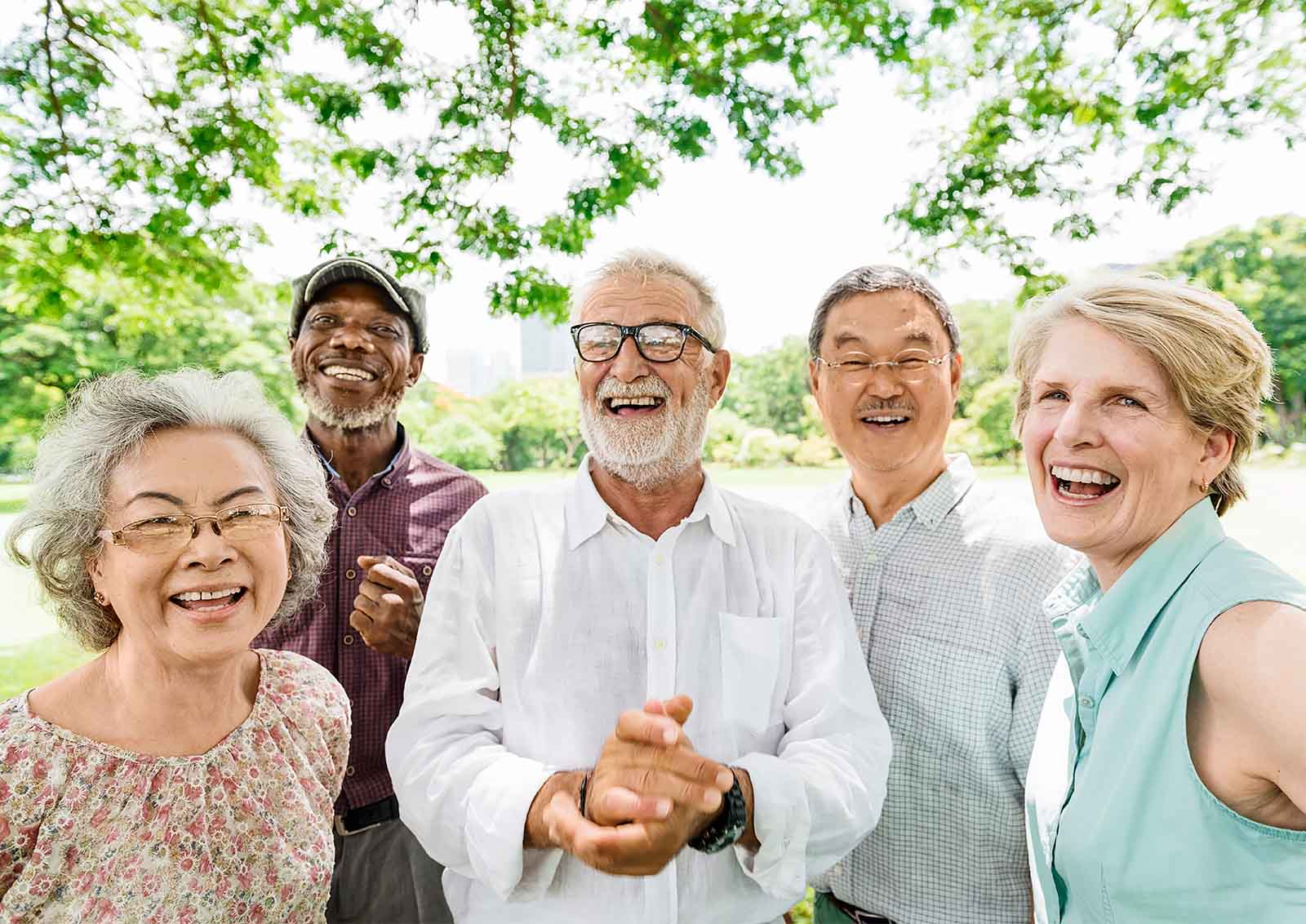A diverse group of happy middle-aged adults gathered und a tree.