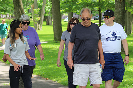 A small group of people engage in conversation while walking in a park.
