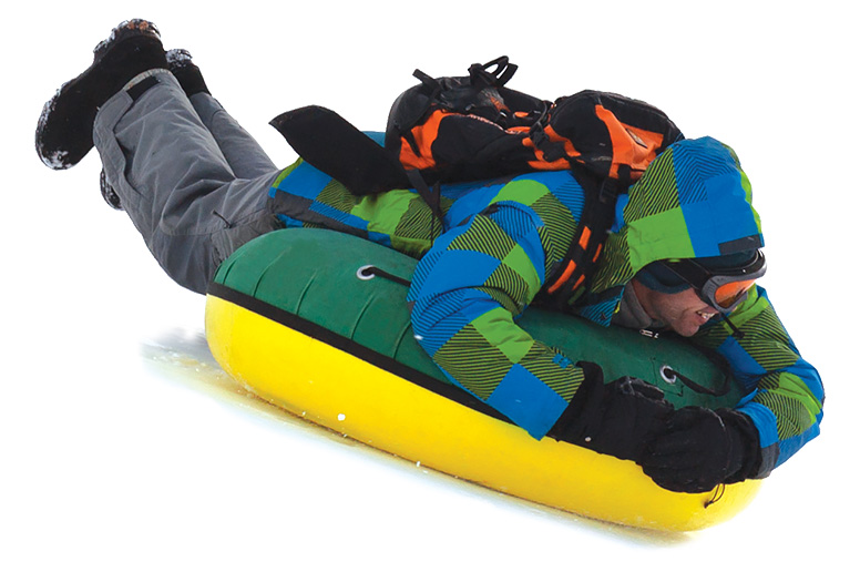 A young adult snowtubing down the mountain.