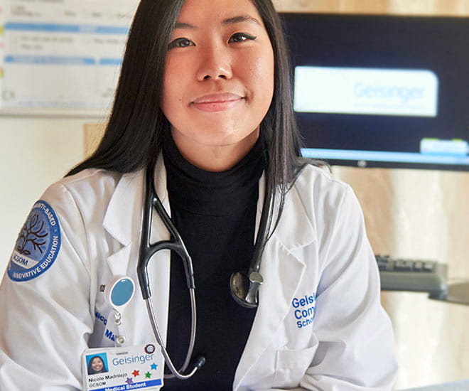 Smiling female physician sitting in exam room.